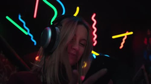 Woman Listens and Laughs with Phone in Neon Light