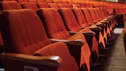 Row of Empty Spectator Chairs with Raised Seats in an Empty Auditorium