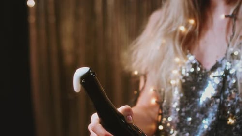 Young Woman Opens Bottle of Champagne Indoors