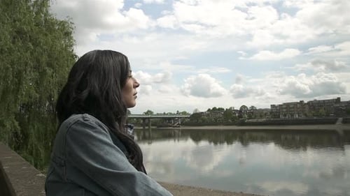 Latina tourist looking at the river Thames and Putney Bridge in London, smiling and having a great t