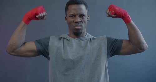 Young Man Flexing Biceps with Red Hand Wraps