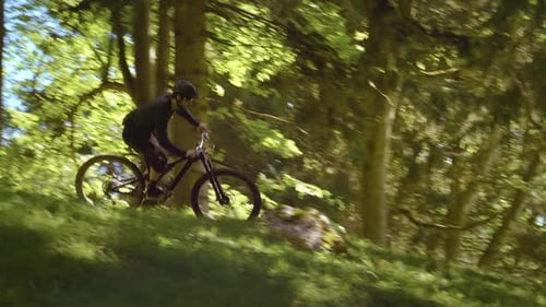 Amazing shot of a biker with MTB E-bike biking down the hill in the forest.