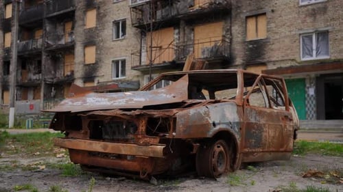 Rusty Burnt Down Car at Bombed Residential Building Outdoors on Kiev Street in Ukraine
