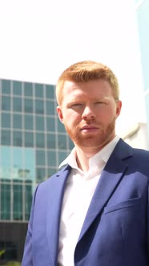Businessman Leaning Outside a Financial Building Looking Up
