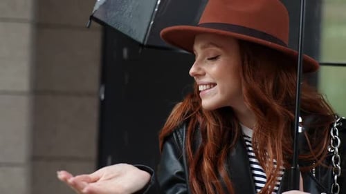 Closeup Face of Cheerful Redhead Young Woman in Hat Standing with Transparent Umbrella in City