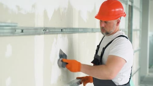 Man Applying Plaster to Wall in Construction Setting