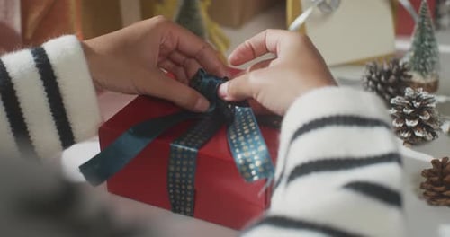 Close up of girl hands wrapping present gift box winter christmas decorations on table.