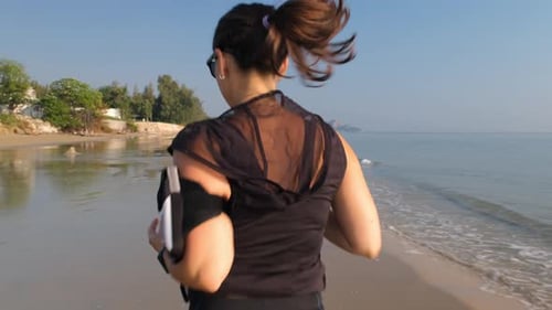 Rear View of Sporty Woman Running Along the Beach