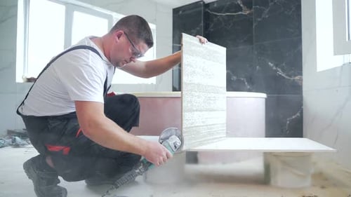 Construction Worker Cutting Tile with Power Tool Indoors