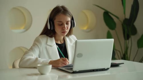Woman Working on Laptop with Headphones at Home
