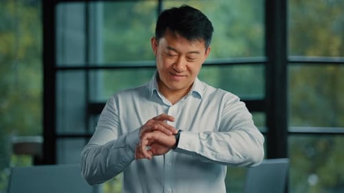 Smiling Man Adjusts Smart Watch in Modern Office