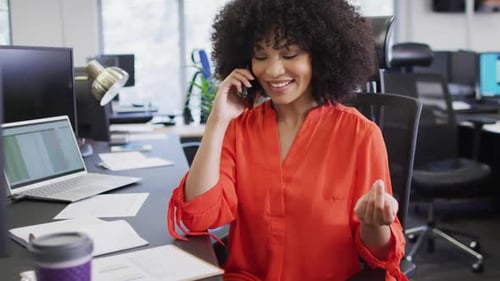 Happy african american businesswoman talking on smartphone in office, slow motion