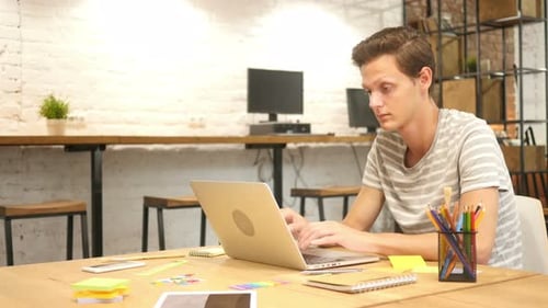 Young Man Celebrating Success While Using Laptop in Office