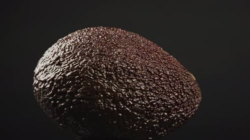 Close-Up Of Ripe Dark Brown Avocado Rotating On Dark Background