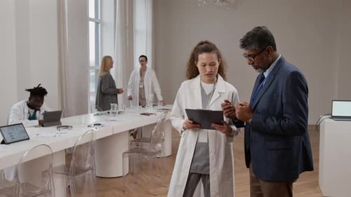 Medical Professionals Discussing Clipboard in Modern Conference Room