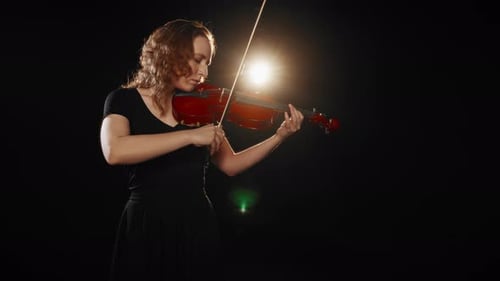Young Woman Plays Violin in Dark Studio