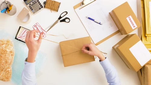 Woman tying rope around parcel box for delivery at post office