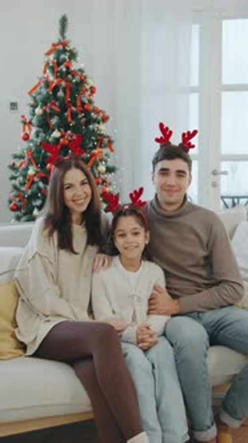 Family Portrait During the Holiday Season with Festive Antler Headbands Beside a Decorated Christmas