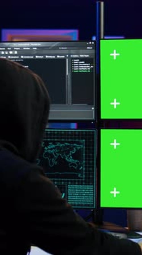 Vidéo verticale en gros plan d'un hacker exécutant du code dans un appartement sur des écrans de PC
