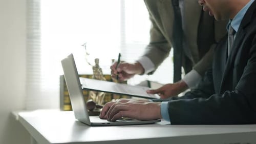 Businessmen Collaborate On Legal Document In Office