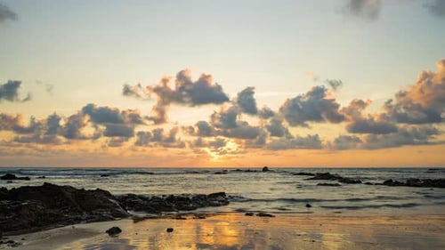 Zeitraffer eines dramatisch Sonnenuntergangs mit orangefarbenem Himmel an einem bewölkten Tag am Meer.
