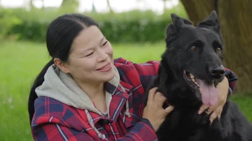 Woman Petting a Black German Shepherd Dog Outdoors