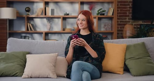 Woman Relaxing on Couch, Using Smartphone at Home