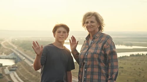 Woman and Child Waving at Sunset in Field
