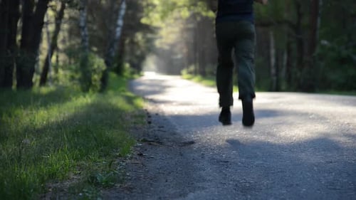 Sport Man Running at Asphalt Road Rural City Park Green Tree Forest and Sun Rays on Horizon