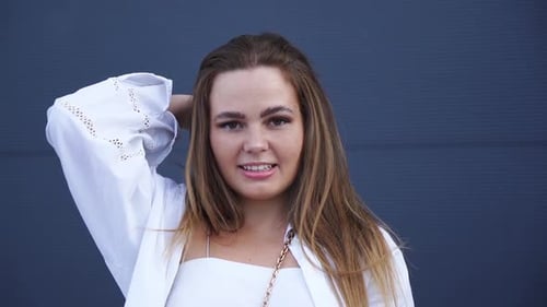 Portrait of young Caucasian girl in white shirt posing for camera. Close-up
