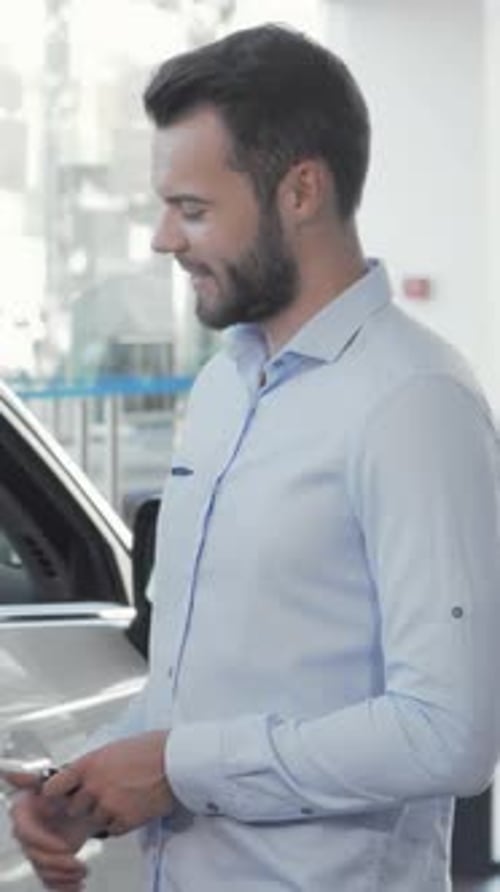 Joyful Woman Beams at the Camera While Her Husband Inspects the Interior of Their New Car