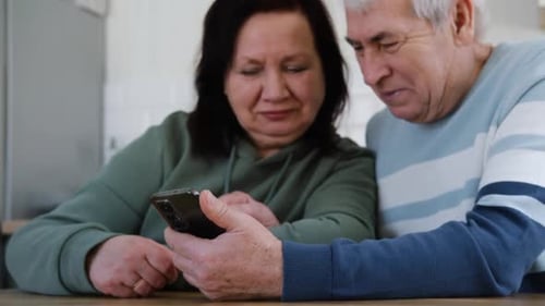 Senior Couple Enjoying Mobile Phone Together at Home