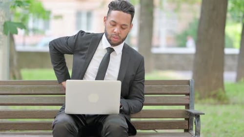 Man in Suit Works on Laptop in Park