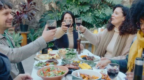 Companhia de amigos levantando taças de vinho em um jantar ao ar livre