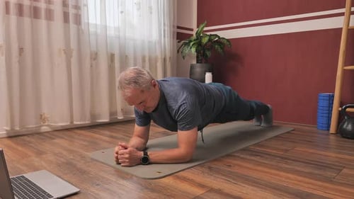 Man Works Out Doing Plank Exercise in Living Room