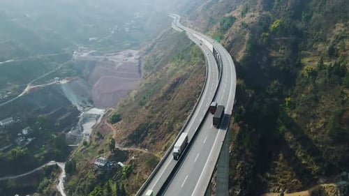 Seitenansicht von Lastwagen, Autos, Fahrzeugen, die eine doppelspurige Autobahnbrücke auf der Autobahn in den Bergen überqueren