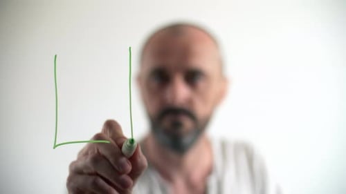 Caucasian Guy Uses Green Marker on a Window Surface