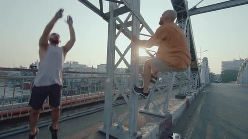 Two Parkour Athletes Climbing on City Bridge