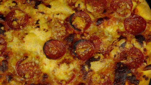 Top down shot of a cooked pizza with pepperoni and melted cheese. Delicious gastro or pub food.