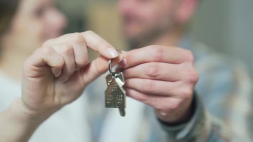 close up of the hands happy married couple holding keys to a new apartment. family bought a house