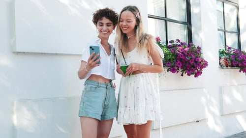 Two Young Women Looking at Phone Together