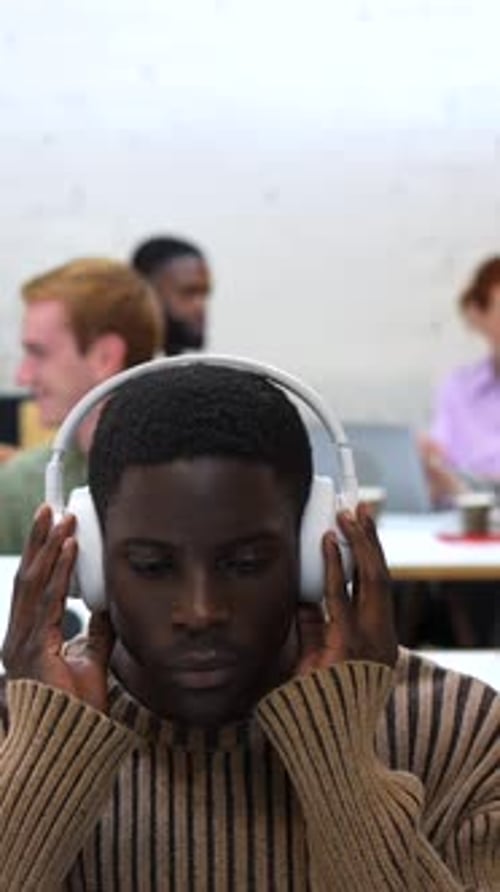 African Man Working Using Laptop and Headphones in a Coworking