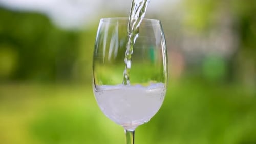 A glass of water is being poured into a wine glass