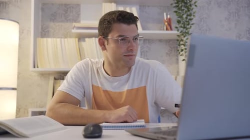 Young Man Studying at Desk with Laptop