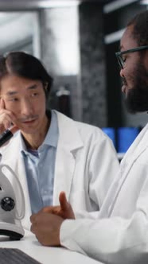Vertikales Videoteam multiethnischer Mikrobiologen arbeitet im Labor mit Molekularmikroskop