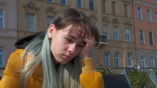 Fille malheureuse sur un banc contre la rue