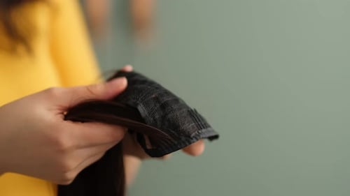 Mulher segura uma peruca morena brilhante nas mãos