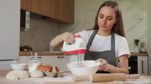 Junge Frau benutzt Mixer beim Schlagen von Eierständern in einer modernen Küche