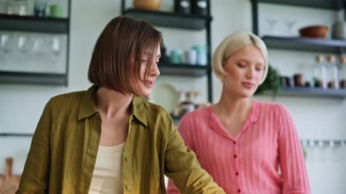 Two Women Cooking Together and Chatting in Kitchen