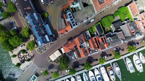 An overhead drone view of a charming canal with boats docked along the edges, a bridge crossing